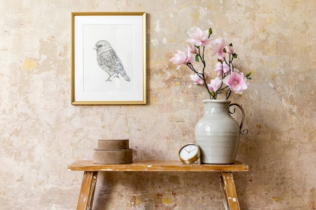 Minimalistyczna kompozycja wnętrza salonu ze złotą ramą, drewnianą ławą, złotym zegarem, magnolią w wazonie i eleganckimi dodatkami osobistymi w nowoczesnym wystroju domu.