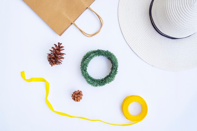 Zdjęcie minimalistyczna koncepcja jesień. torba papierowa, biały kapelusz, lina wstążka, kwiaty sosny, wieniec z krans na białym tle na tle białego papieru. minimalistyczna koncepcja świąteczna