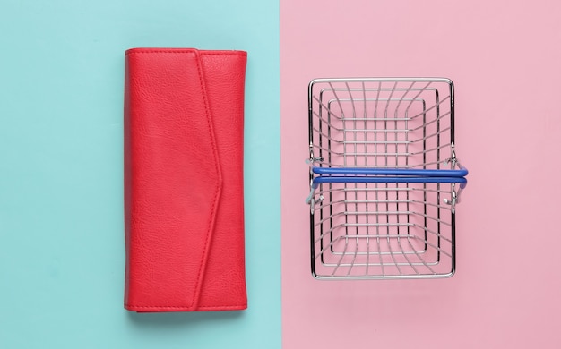 Minimalistyczna koncepcja zakupów Mini kosz na zakupy i czerwony skórzany portfel na różowym niebieskim tle