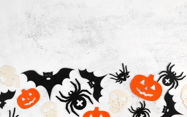Zdjęcie minimalistyczne tło halloween z czaszkami, dynami, nietoperzami, pająkami na białym tle betonowym zaproszenie lub karta na 31 października