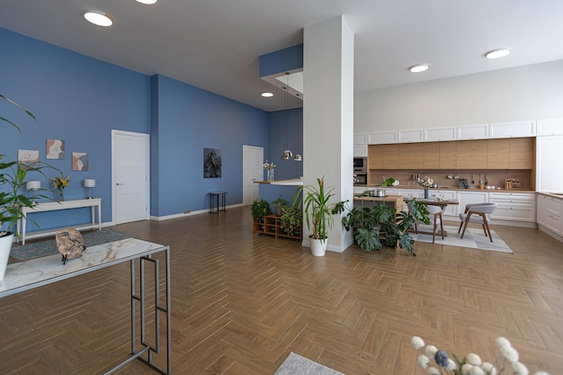 Minimalistyczny nowoczesny wystrój wnętrz ogromne jasne mieszkanie o otwartym planie w stylu skandynawskim w biało-niebieskim i granatowym kolorze z kolumnami pośrodku zawiera aneks kuchenny gabinet i salon