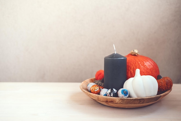 Minimalna dekoracja świąteczna halloween z cukierkami dyniowymi czarnymi świecami na drewnianym stole w pomieszczeniu
