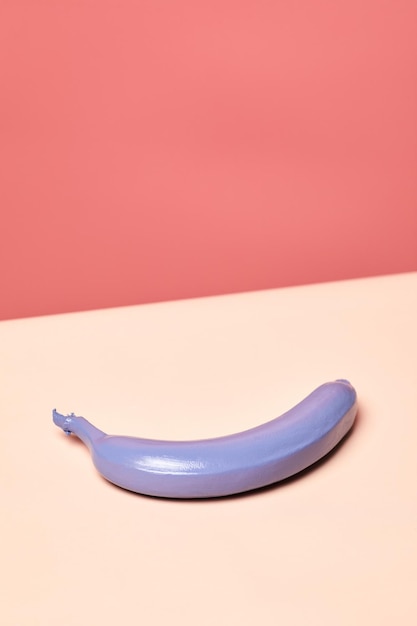 Minimalne ujęcie pojedynczego fioletowego banana na różowym tle w żywych kolorach kopiuje przestrzeń