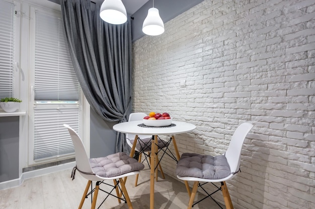 MIŃSK BIAŁORUŚ WRZESIEŃ 2019 Wnętrze nowoczesnej luksusowej kuchni ze stołem gościnnym w loftowych apartamentach typu studio w minimalistycznym stylu z białym kolorem w ceglanej ścianie