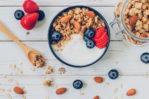 Zdjęcie miska granola z jogurtu,? wie? ych owoców jagodowych, jagodami i orzechów na drewnianych tabeli.