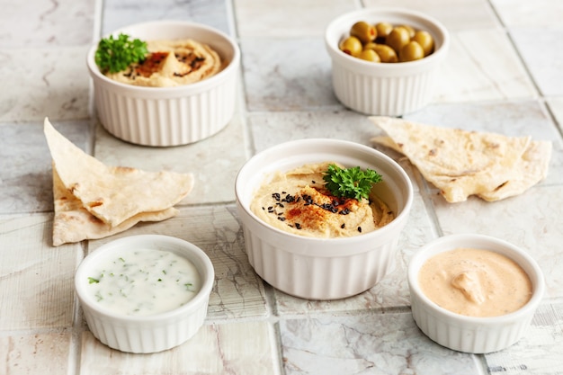 Miska hummusu, tradycyjnego żydowskiego, arabskiego, bliskowschodniego jedzenia z ciecierzycy z głębią iz pitą flatbread na tle płytek ceramicznych. Zbliżenie, selektywne skupienie