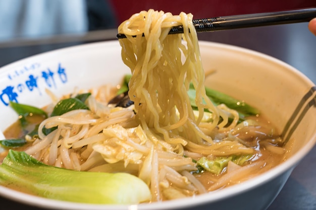 Miska ramenu z pałeczkami i tabliczką z napisem „ramen”.