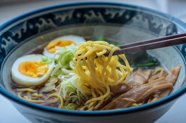 Miska ramenu z parą pałeczek trzymających miskę makaronu ramen.