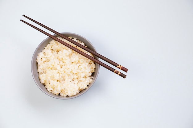 Miska ryżu z pałeczkami na neutralnym tle