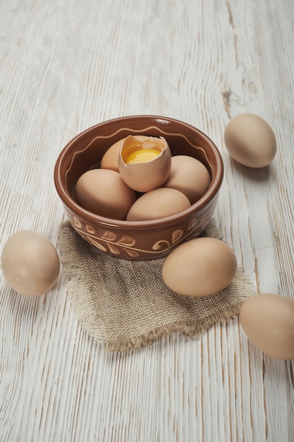 Miska surowych jaj kurzych na drewnianym tle