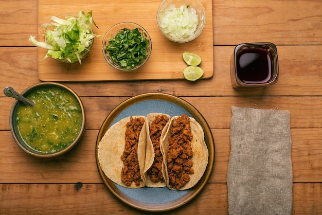 Miska tacos z marynowaną wołowiną z salsą verde i warzywami na drewnianym stole Tacos de adobada