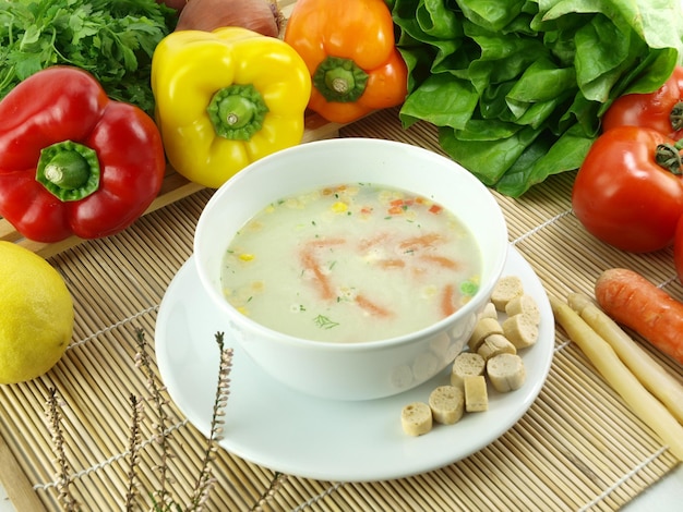 Miska zupy z marchewką i innymi warzywami na stole.
