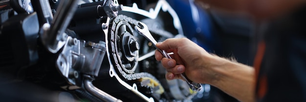 Zdjęcie mistrz mechanik naprawiający motocykl z kluczem zbliżenie
