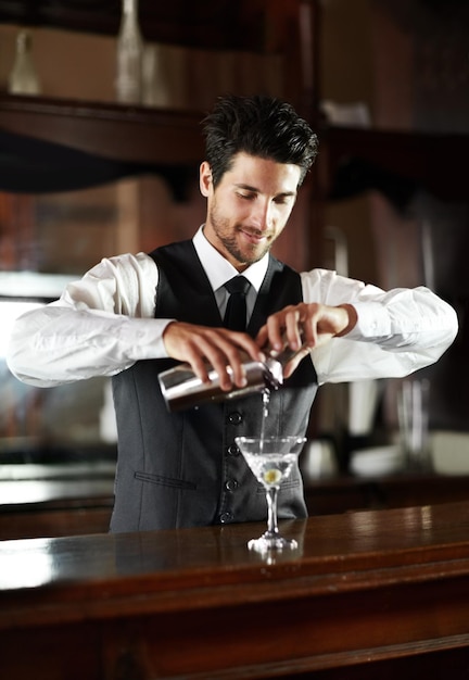 Mistrz miksologa Przystojny młody barman przygotowujący koktajl dla klienta