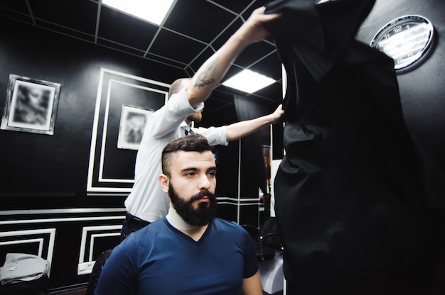 Mistrz przycina włosy i brodę mężczyzn w zakładzie fryzjerskim