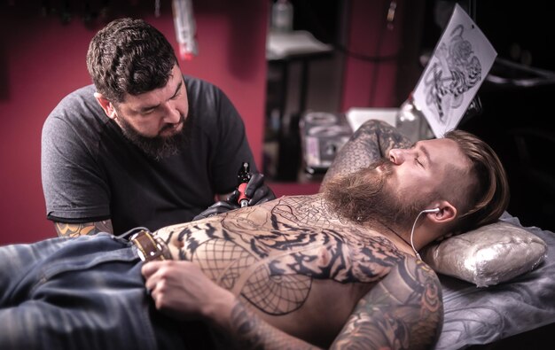 Mistrz sztuki tatuowania przedstawiający proces wykonywania tatuażu w studio tatuażu.