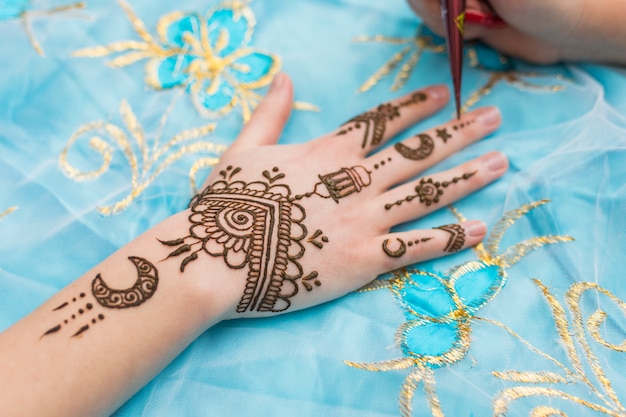 Zdjęcie mistrz tatuażu mehndi rysuje na kobiecej dłoni