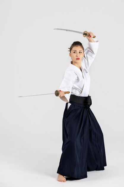 Zdjęcie mistrzyni aikido kobieta w tradycyjnym kimono hakama samuraja z czarnym pasem z mieczem katana na białym tle zdrowy styl życia i sport koncepcja