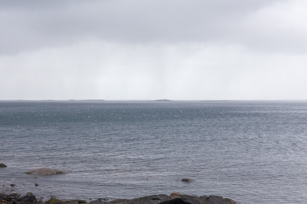 Mistyczny fiord w Norwegii z górami i mgłą wiszącą nad wodą w dzień polarny