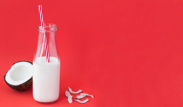 Mleko kokosowe w szklanej butelce na czerwonym tle Closeup Copy space
