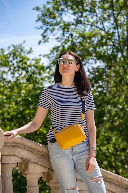 Młoda 30-letnia kobieta w jeansowej koszulce i żółtej torbie spacerująca po parku Ciutadella w Barcelonie Dziewczyna podróżuje po Hiszpanii