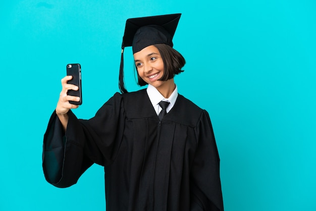 Młoda Absolwentka Uniwersytetu Dziewczyna Na Odosobnionym Niebieskim Tle Robi Selfie
