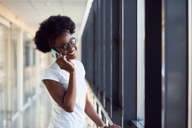 Młoda african american kobieta pasażera w ubranie jest na lotnisku z telefonem.