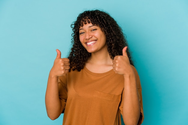 Młoda Afro amerykańska kobieta na białym tle uśmiechając się i podnosząc kciuk do góry