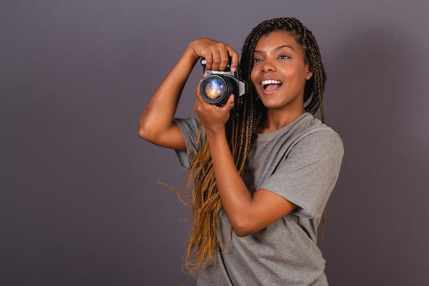 Młoda afro brazylijska kobieta fotograf uśmiecha się trzymając aparat fotograficzny