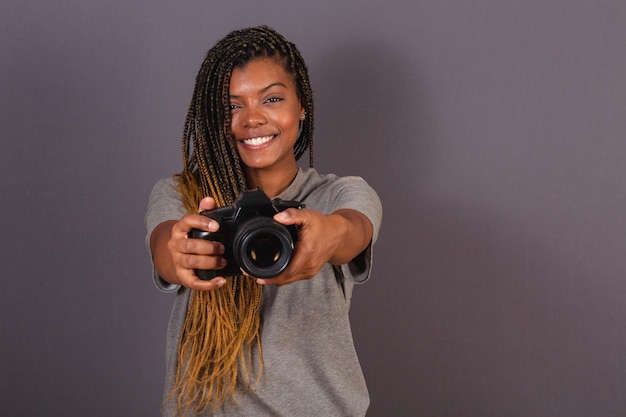 Młoda afro brazylijska kobieta fotograf uśmiecha się trzymając aparat fotograficzny