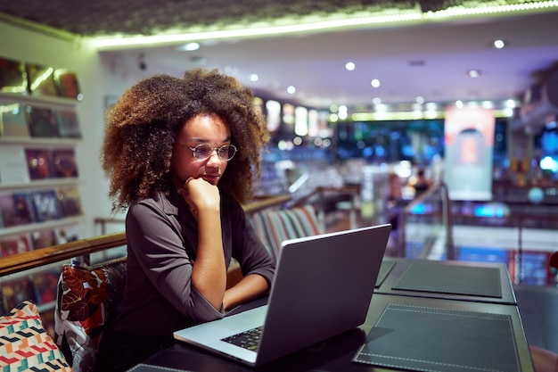 Młoda Afro-czarna Brazylijska Kobieta Siedząca W Stołówce Bibliotecznej Czytająca Ekran Swojego Notatnika