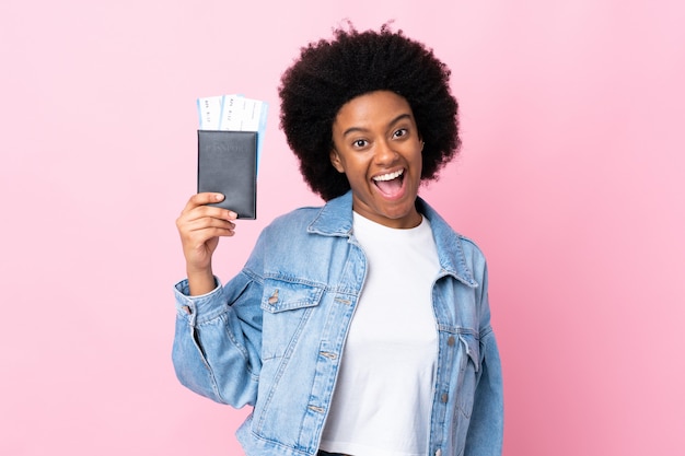 Młoda Afroamerykanin kobieta na białym tle na różowy szczęśliwy w wakacje z paszportem i biletami lotniczymi