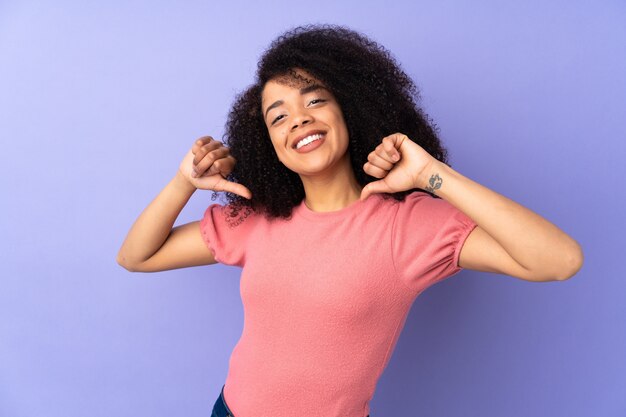 Młoda Afroamerykanin kobieta na fioletowym tle dumny i zadowolony z siebie