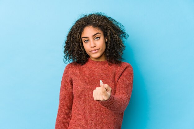 Młoda Afroamerykanin kręcone włosy kobieta wskazując palcem na Ciebie, jakby zapraszając, podejdź bliżej.