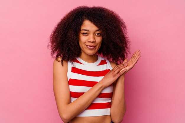 Młoda Afroamerykanka Na Różowym Tle Czuje Się Energicznie I Wygodnie, Zacierając Ręce Pewnie.