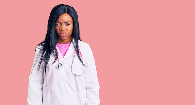 Młoda Afroamerykanka nosząca stetoskop lekarza sceptyczna i nerwowa, marszcząca brwi zdenerwowana z powodu problemu. negatywna osoba.