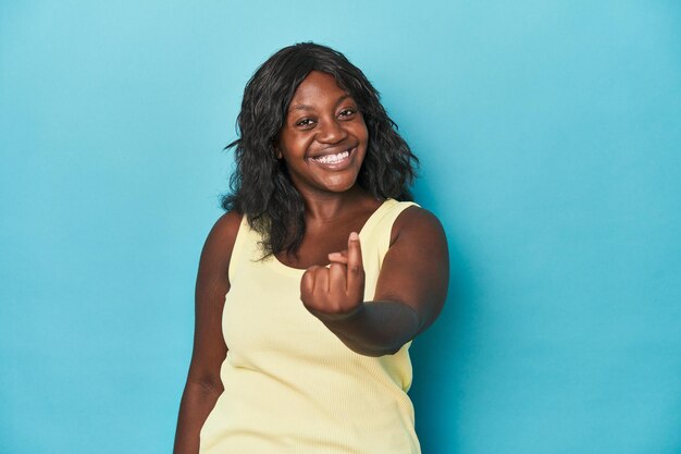 Młoda Afroamerykanka o krągłych kształtach wskazuje na ciebie palcem, jakby zapraszała do zbliżenia się