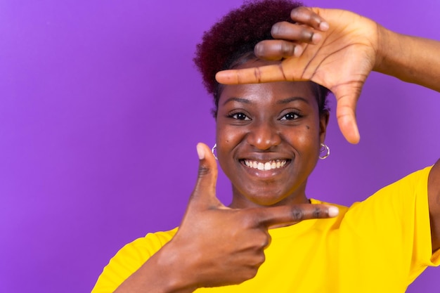 Młoda Afroamerykanka odizolowana na fioletowym tle z kwadratem gestu z palców w studio