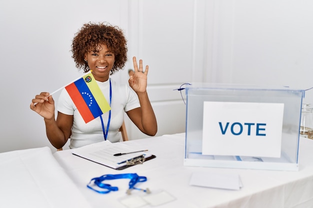 Młoda Afroamerykanka podczas wyborów w kampanii politycznej trzymająca flagę Wenezueli robi znak ok z palcami uśmiechniętymi przyjaznymi gestami doskonałego symbolu