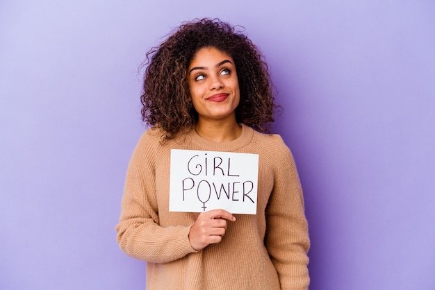 Młoda Afroamerykanka trzyma afisz Girl Power na fioletowym tle, marząc o osiągnięciu celów i celów