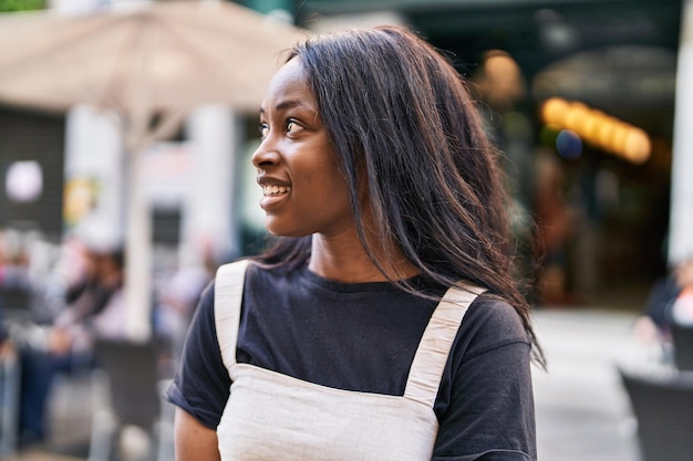 Młoda Afroamerykanka uśmiecha się pewnie stojąc na ulicy