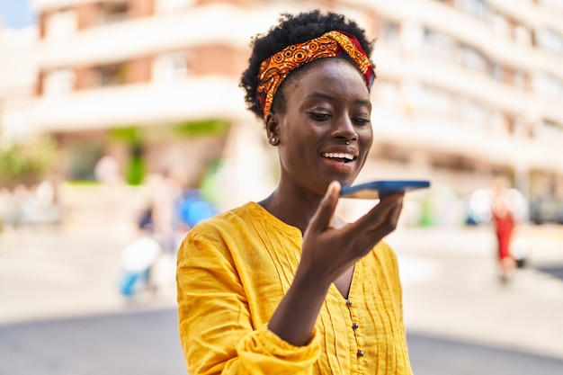 Młoda Afroamerykanka, uśmiechnięta, pewna siebie, rozmawiająca przez smartfon na ulicy