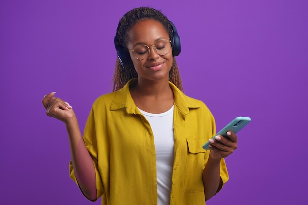 Młoda Afroamerykanka w słuchawkach do słuchania muzyki i trzyma telefon