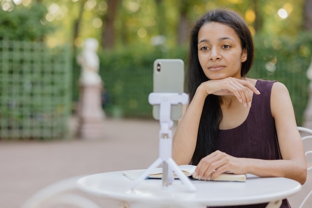 Młoda Afroamerykanka z Tysiąclecia ogląda webinarium lub transmisję na żywo ze swojego smartfona