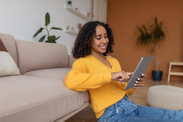 Młoda Afroamerykańska Dama Korzystająca Z Nowej Aplikacji Mobilnej Na Cyfrowym Tablecie W Domowej Przestrzeni Kopii