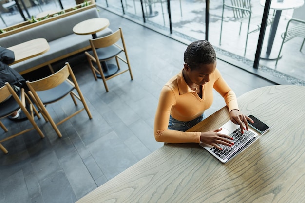 Młoda afrykańska freelancerka pracująca na laptopie siedząc w coworkingu