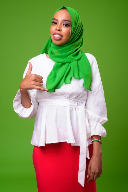 Młoda afrykańska muzułmańska kobieta przeciwko klucz chroma z zieloną ścianą