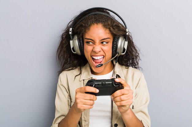 Młoda amerykanin afrykańskiego pochodzenia kobieta używa hełmofony i kontrolera gier