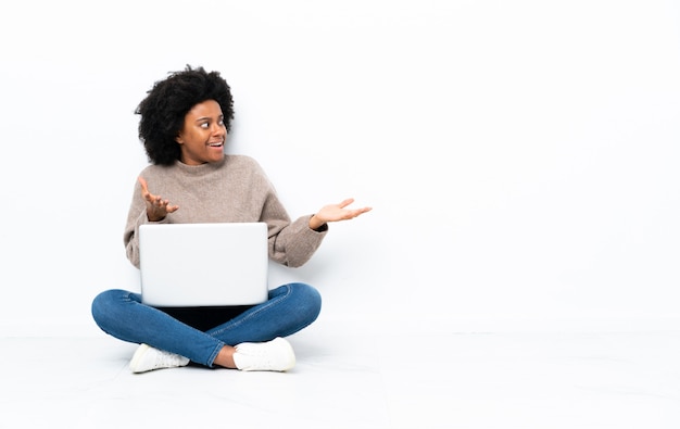 Młoda amerykanin afrykańskiego pochodzenia kobieta z laptopu obsiadaniem na podłoga z niespodzianka wyrazem twarzy