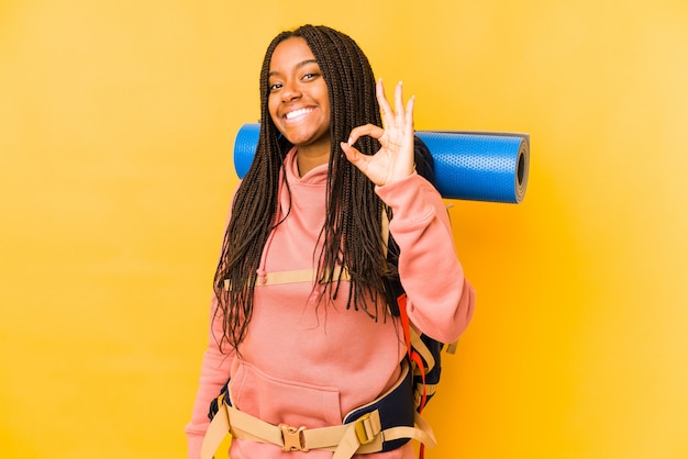Młoda amerykanina afrykańskiego pochodzenia backpacker kobieta odizolowywał rozochoconego i ufnego pokazuje ok gest.